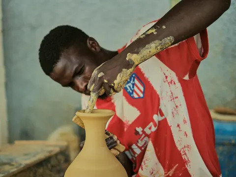 A potter shaping clay on a spinning potter's wheel