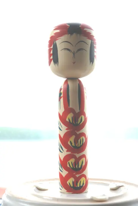 A traditional Japanese kokeshi wooden doll with painted floral patterns